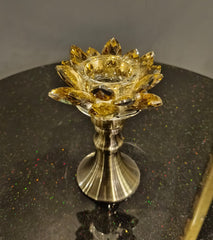 Decorative candle holder with gold and silver design on a dark surface