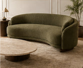 Olive Arc curved three-seater sofa in olive bouclé upholstery with rounded arms, shown in a warm contemporary living room.