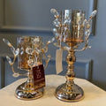 Gold-tone metal candle stand with amber glass shade and sculpted branch details