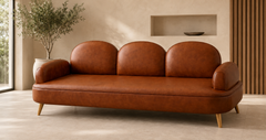 The Aria Leather Sofa in cognac-brown leather with three arched backrests, rounded armrests, stitched detailing, and tapered brass-finish legs