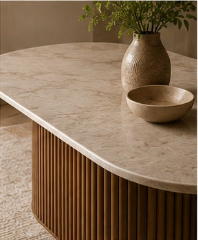 Close-up detail of the Elara oval dining table, highlighting the light sintered stone top and vertical ribbed Sheesham wood base.