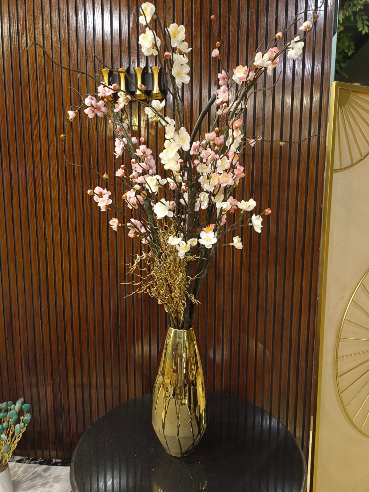 Golden ceramic flower vase styled on a shelf
