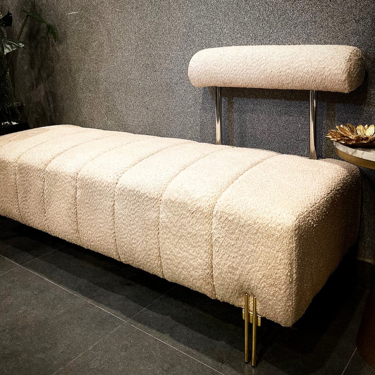 Upholstered bench with gold legs styled in a room