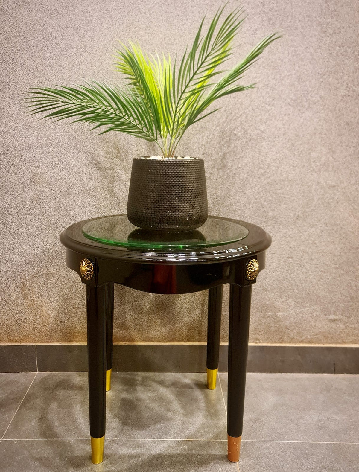 Round wooden coffee table with glass top styled in a living room