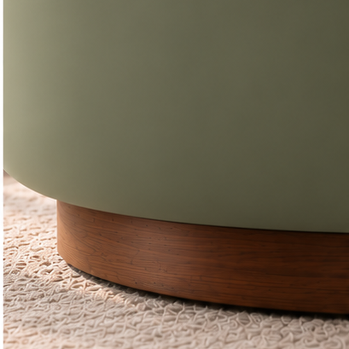 Close-up of smooth sage upholstery and solid wood circular base on Aurelia Cocoon Lounge Chair