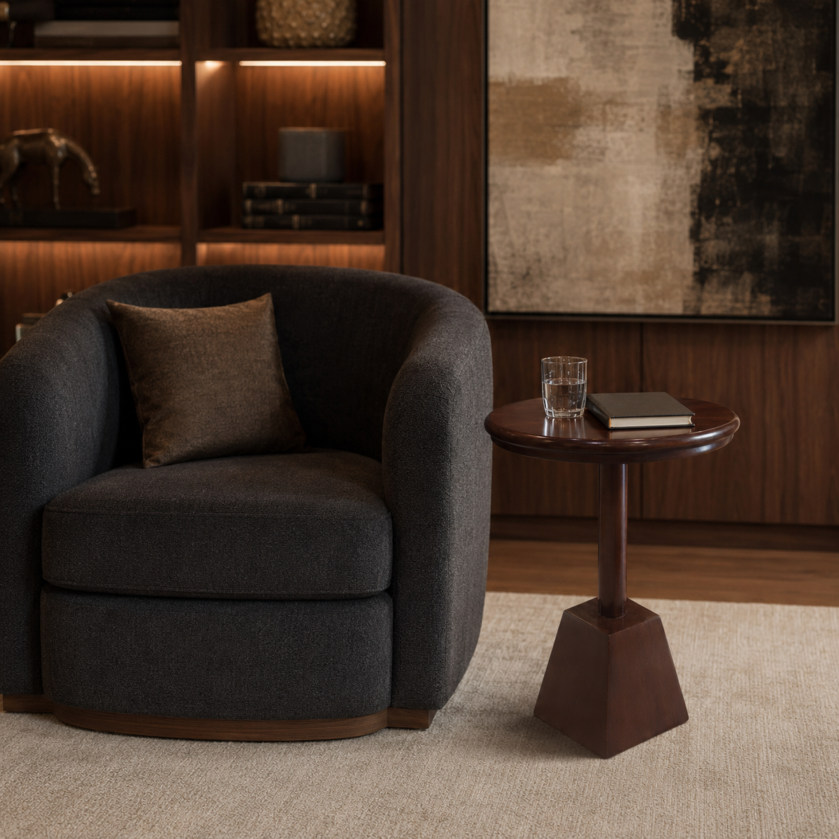 A dark charcoal gray upholstered accent chair with a brown throw pillow, positioned next to a round dark wood side table in a warm, modern living room setting.